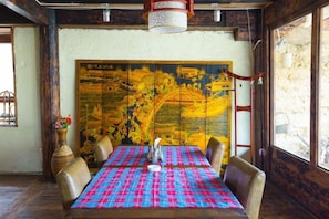 Un coin repas avec une table dressée pour quatre personnes, un grand tableau décoratif au mur et une fenêtre offrant une belle vue.