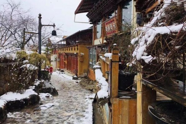 A narrow cobblestone path leading to a traditional building with a red door and a signboard. - Shangri-La Chang Palace (Shangri-La)