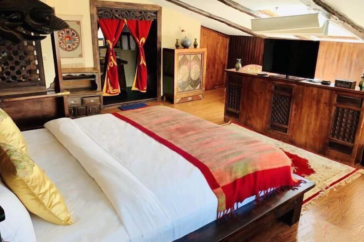 Une chambre avec un lit, des meubles en bois, une télévision et un rideau rouge.
