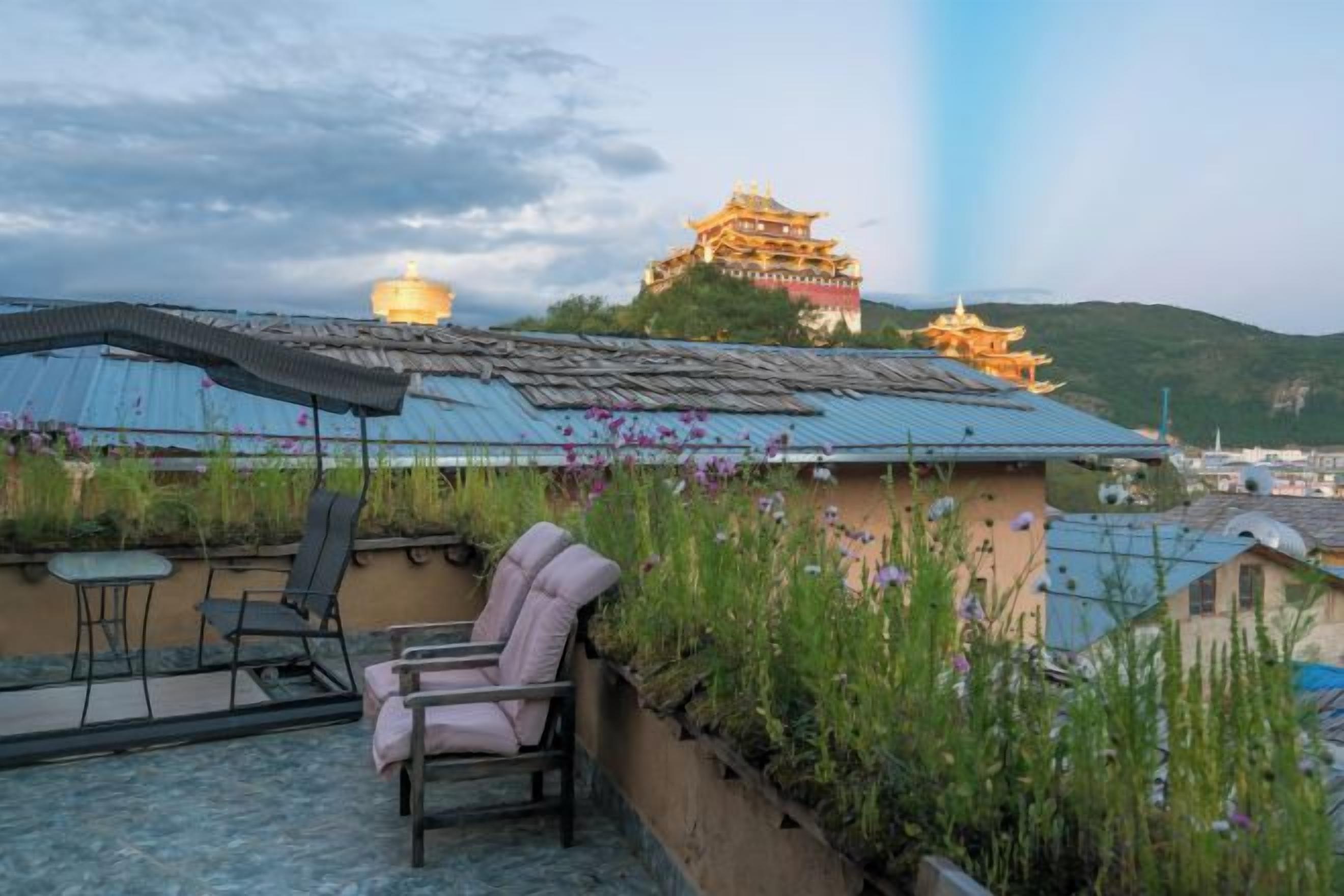 A rooftop terrace with a traditional building in the background, a table, and two chairs.