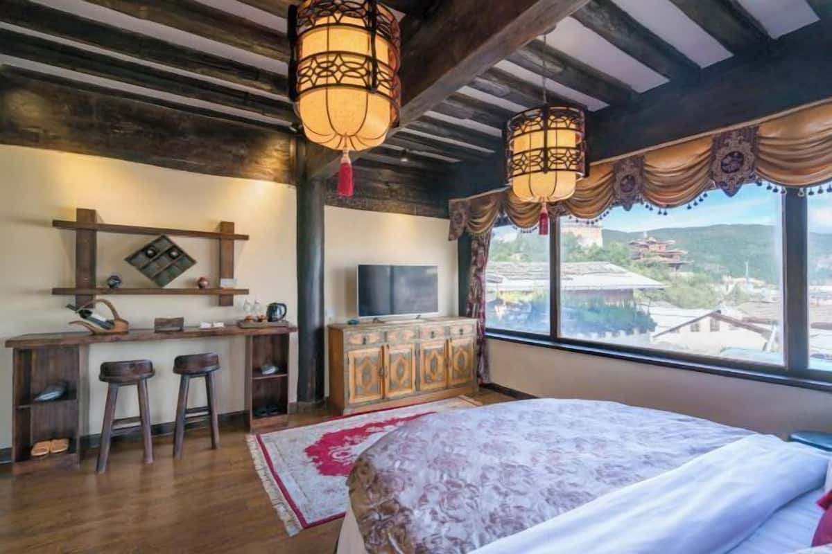 Une chambre avec un lit, un bureau avec une télévision et une vue sur un bâtiment traditionnel.