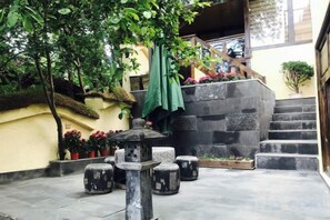 Un patio con un banco de piedra, una pequeña fuente y una escalera que conduce a un nivel superior.