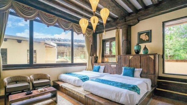 A room with a large bed, two chairs, a wooden coffee table, and a view of the outside. - Shangri-La Chang Palace (Shangri-La)