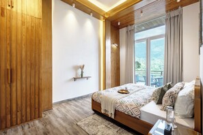 Une chambre avec une armoire en bois, un lit avec une literie à motifs, une table de chevet et une vue sur la verdure à l’extérieur.