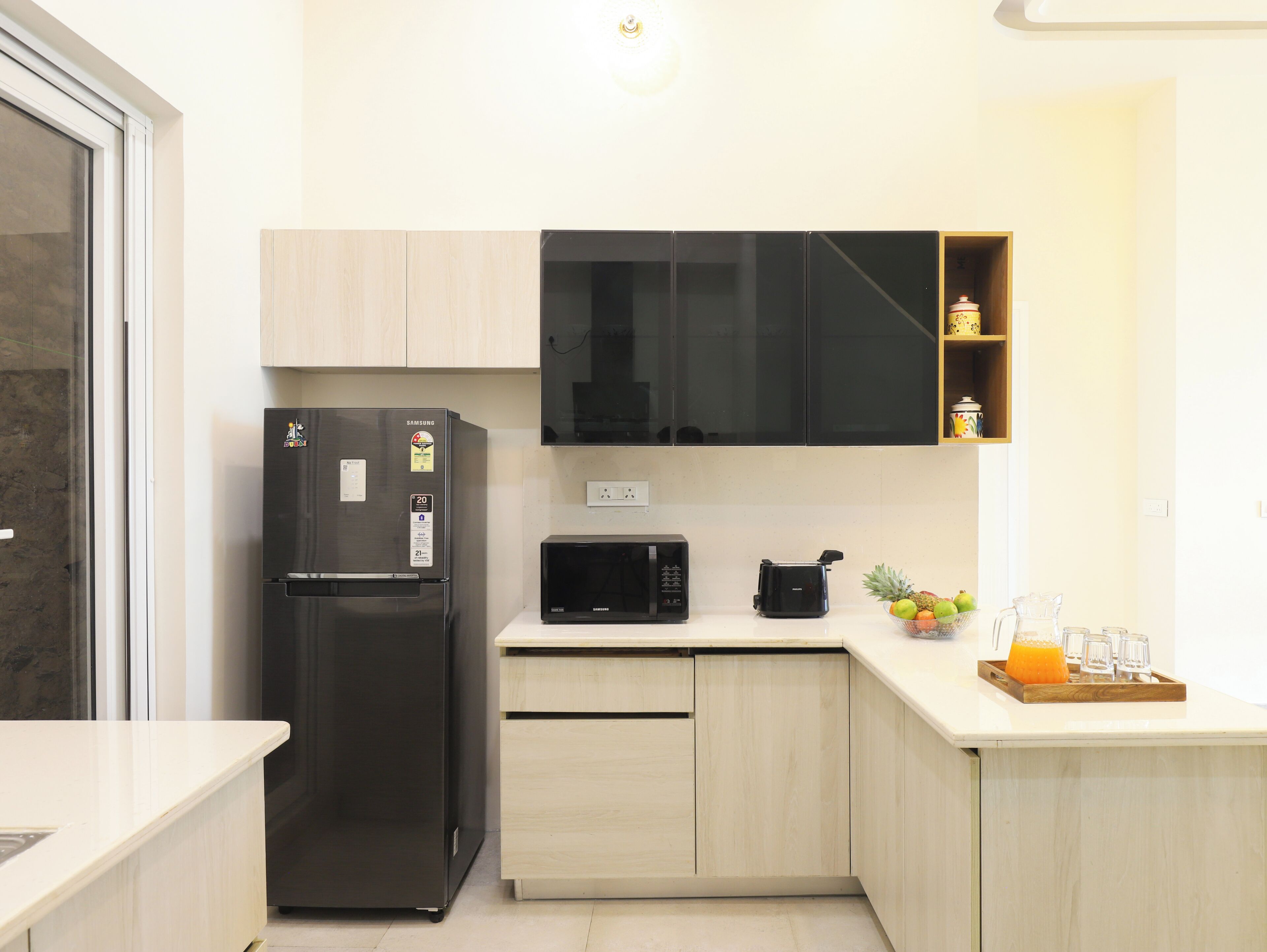 Una cucina moderna con frigorifero nero, forno a microonde e pensile in legno.