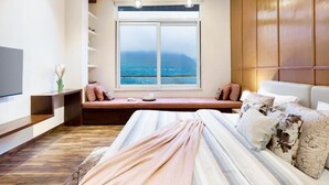Une chambre à coucher avec un lit, une fenêtre donnant sur un beau paysage, une télévision et un plafond en bois.