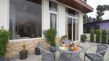 A patio with wicker furniture, potted plants, and a dining table set with plates and glasses.