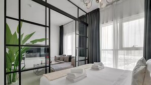 Une chambre d’hôtel moderne dotée d’un grand lit, d’un canapé, d’une table à manger et offrant une vue sur le balcon.