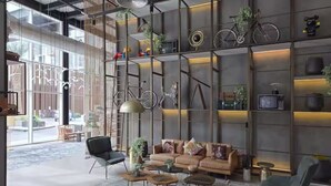 Un intérieur moderne avec un canapé, une table basse et des fauteuils, une grande fenêtre et un mur agrémenté d’étagères et d’objets décoratifs.