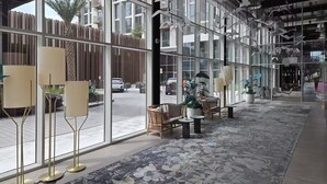 Un hall d’hôtel moderne, doté de grandes fenêtres, de lampadaires et d’espaces aménagés avec des sièges.