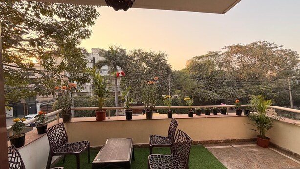 A rooftop terrace with a table and chairs, potted plants, and a view of the cityscape. - VR RESIDENCY 83 (Gurugram)