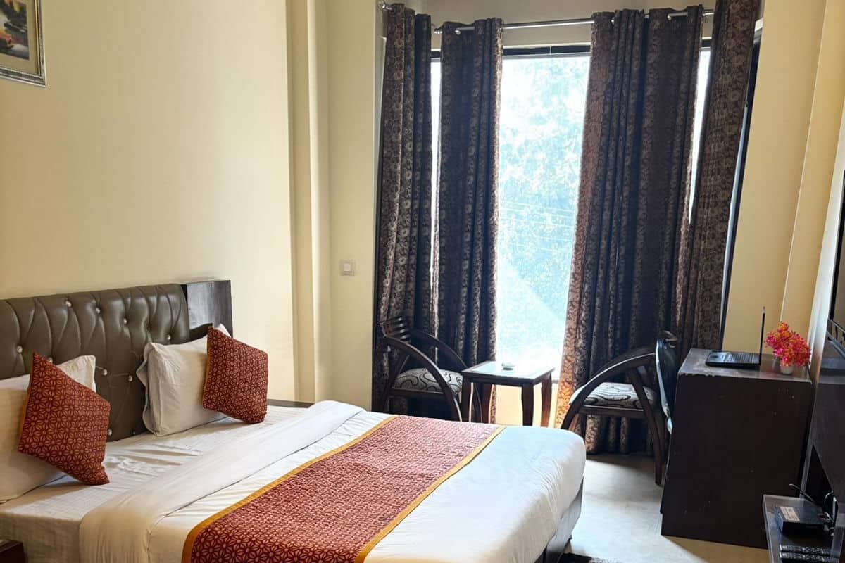 Habitación de hotel con una cama grande, un escritorio, una silla y vistas al exterior.