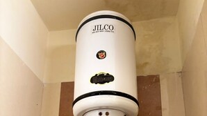 A white water heater mounted on a tiled wall with a visible brand logo and a control panel. - VR RESIDENCY 83 (Gurugram)