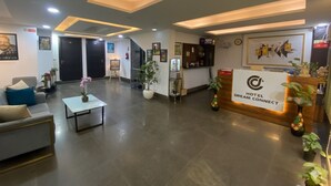 Un hall de hotel con mostrador de recepción, sofás, una mesa de centro y plantas en macetas.