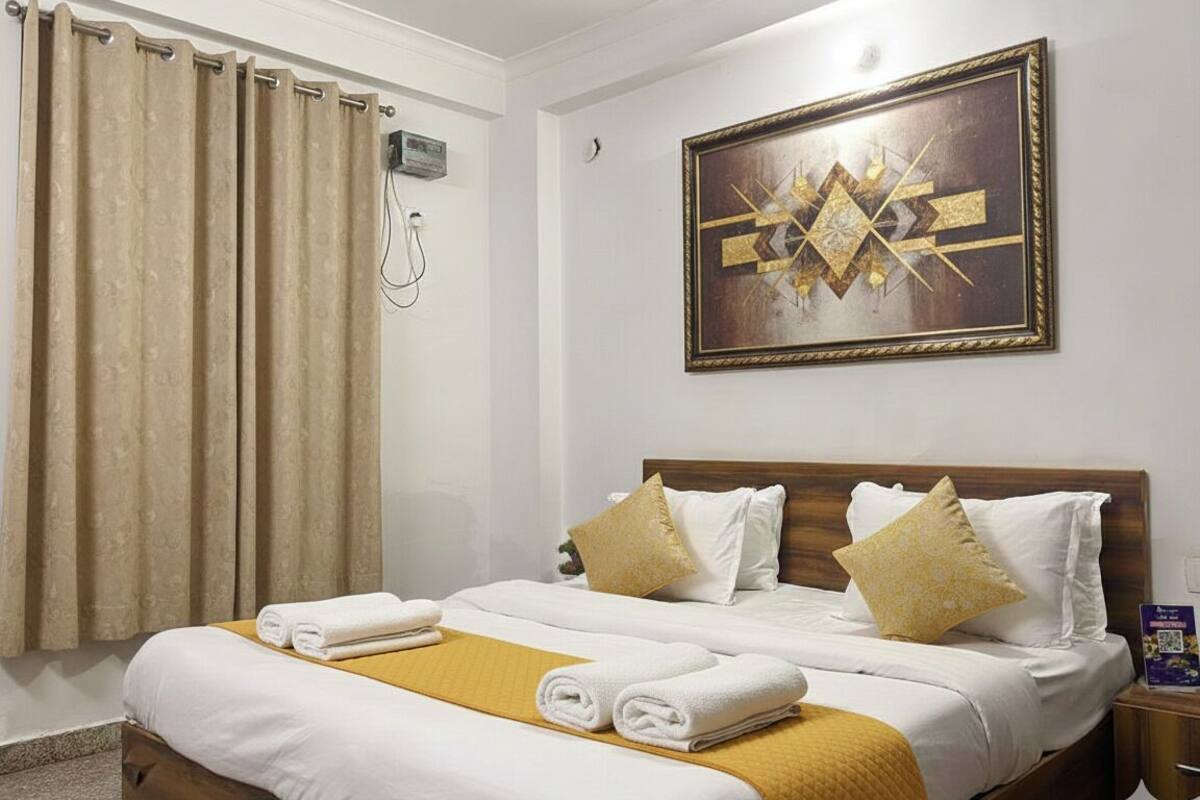 A hotel room with a bed, curtains, a painting, and a bedside table.
