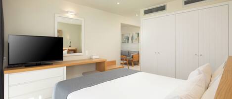 A modern hotel room with a bed, a TV, a desk, and a wardrobe.