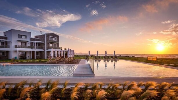 A modern hotel with a pool, lounge chairs, and a view of the sunset over the ocean. - Thalassa Suites Corfu (Corfu)