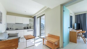 A modern apartment with a kitchenette, a dining area, a living room with a sofa, a wooden table, and a TV. - Thalassa Suites Corfu (Corfu)