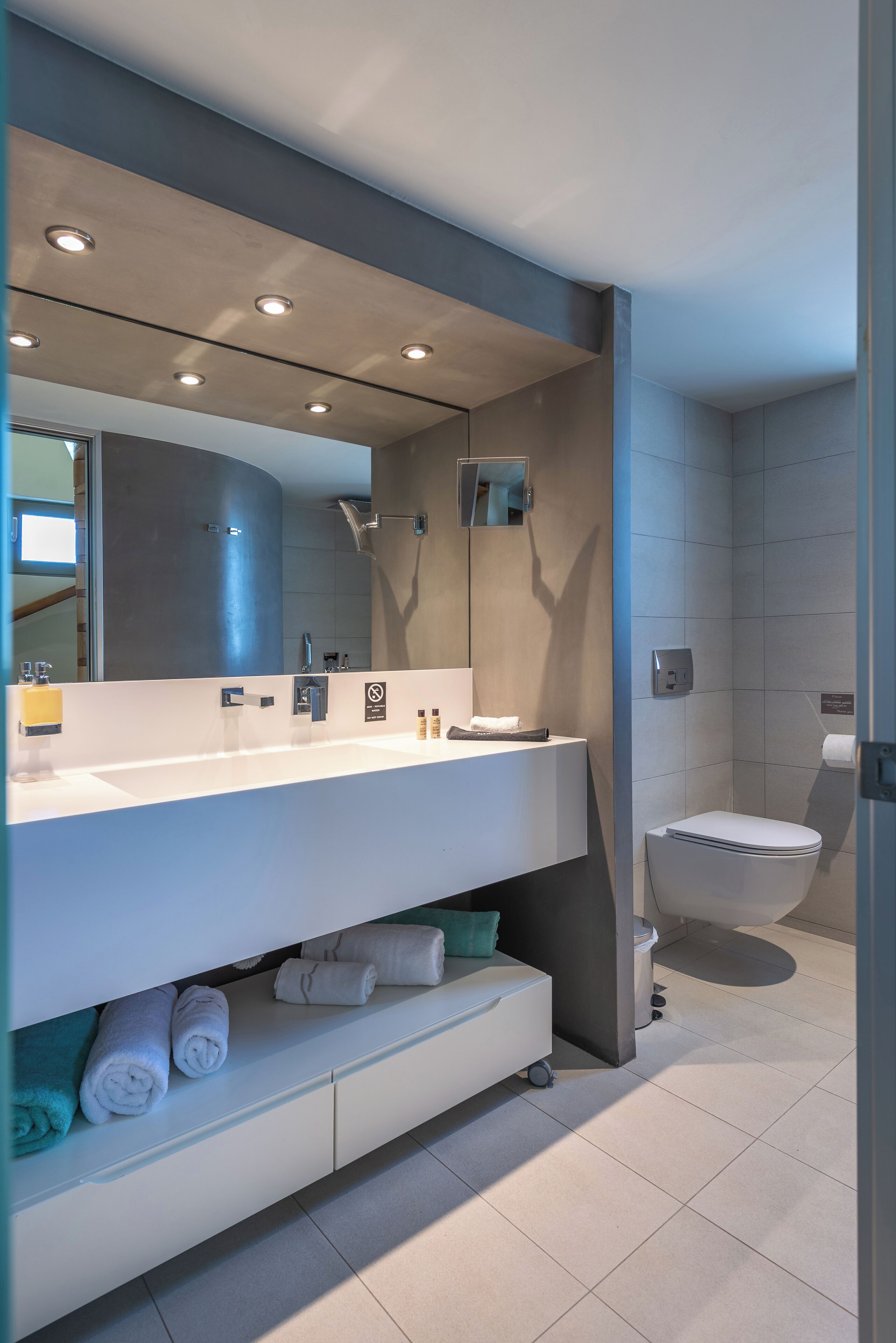 A modern bathroom with a large mirror, a toilet, and a sink.