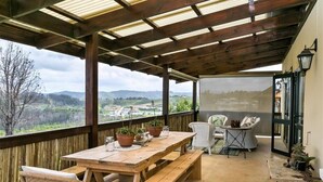 A wooden deck with a table and chairs, potted plants, and a view of the landscape. - Narnia Luxury Self Catering Guest House (Knysna)