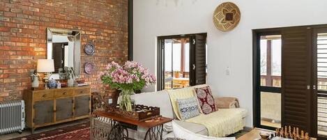 A living room with a brick wall, a chandelier, a sofa, a coffee table, and a chessboard.