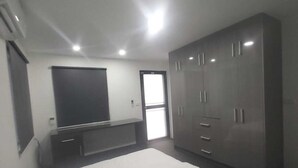 A bedroom with a bed, a wardrobe, a TV, and a door leading to a balcony. - Whitehaven Apartment in Lautoka, Fiji (Lautoka)