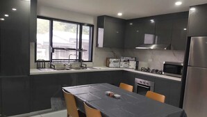 A modern kitchen with dark cabinets, a stainless steel refrigerator, a microwave, and a sink with a window above it. - Whitehaven Apartment in Lautoka, Fiji (Lautoka)