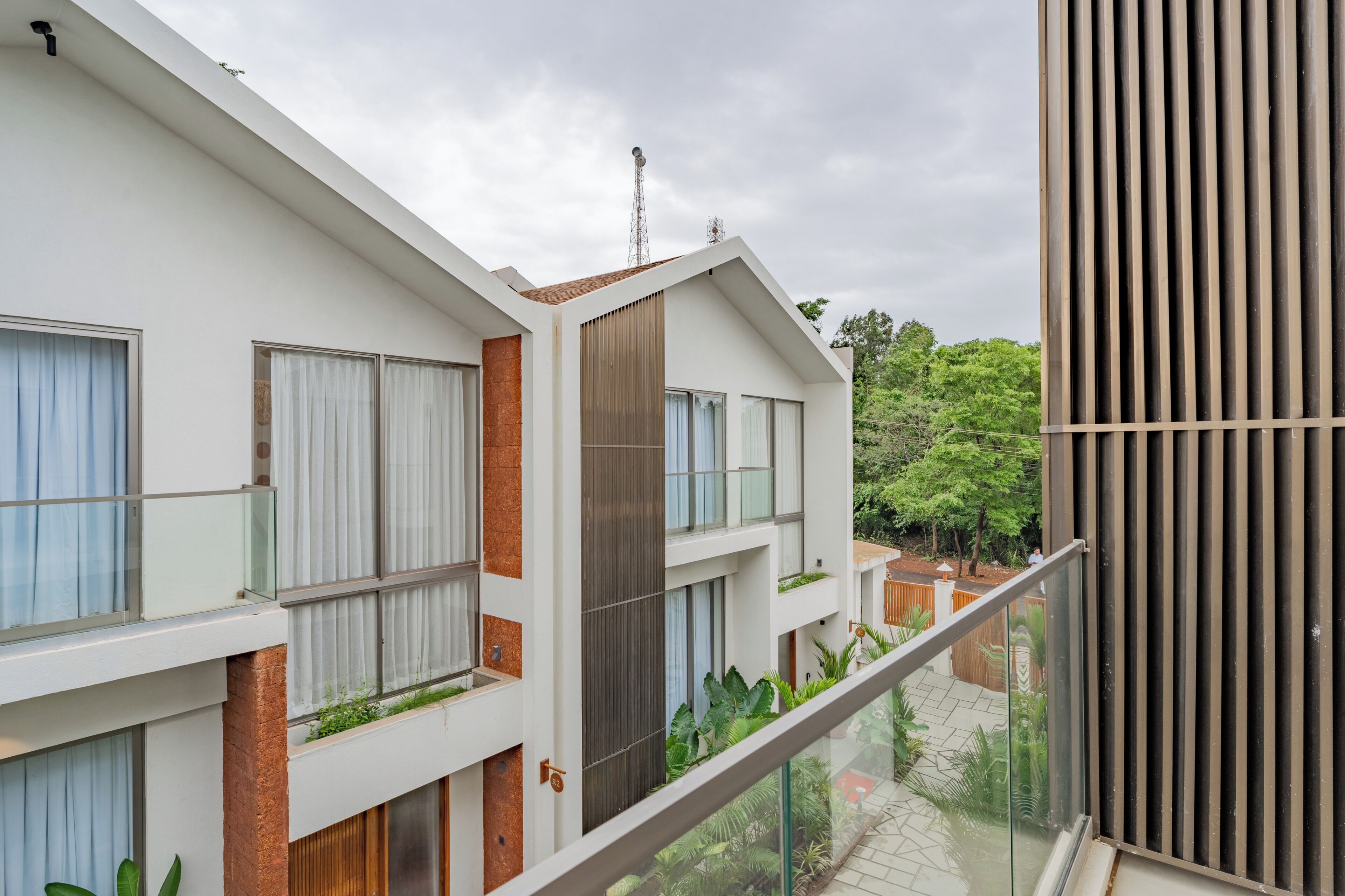 Un immeuble résidentiel moderne à plusieurs étages, doté de balcons, de grandes fenêtres et offrant une vue sur la verdure.