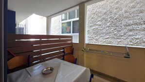 A room with a bed, a window with a view, a table with a metal bowl, and a chair. - 8A - Alexandros Apartment by SDR (Paralia)