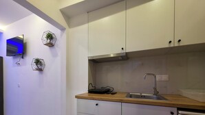 A modern kitchen with white cabinets, a wooden countertop, a stainless steel sink, and a built-in oven. - 8A - Alexandros Apartment by SDR (Paralia)
