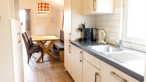 Une cuisine compacte comprenant un coin repas, une machine à café et un évier.