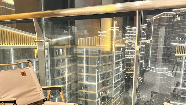 A balcony with two beige canvas chairs, a white storage box, and a glass railing. - GH3-Glory Hieght- Vinhome Grand Park (Ho Chi Minh City)