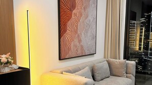 A modern living room with a sofa, a black coffee table, a floor lamp, and a large abstract painting on the wall. - GH3-Glory Hieght- Vinhome Grand Park (Ho Chi Minh City)