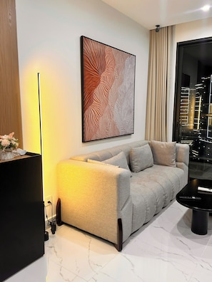 Ein modernes Wohnzimmer mit einer Couch, einem schwarzen Couchtisch, einer Stehlampe und einem großen abstrakten Gemälde an der Wand.