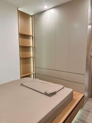 Ein Schlafzimmer mit einem Bett, einer Holzregaleinheit und einem Kleiderschrank mit Schiebetüren.