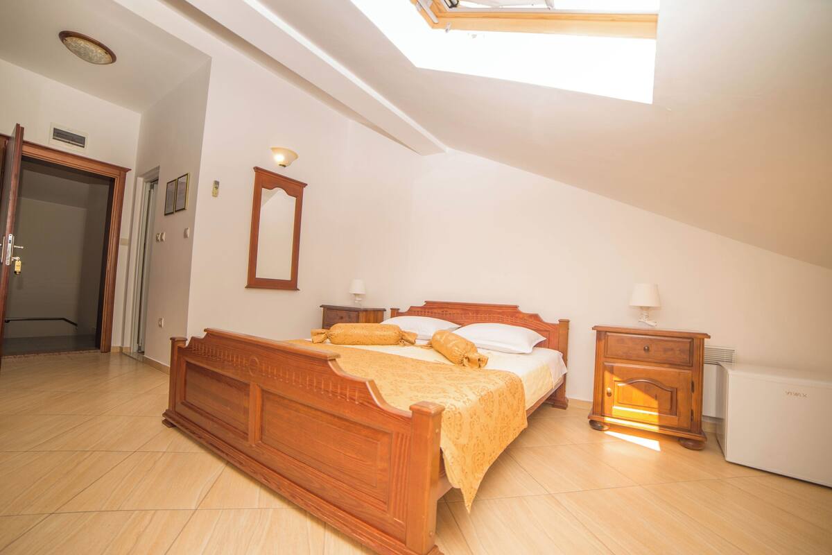 Ein Schlafzimmer mit Dachfenster, einem hölzernen Bett, einem Nachttisch und einer Heizung.