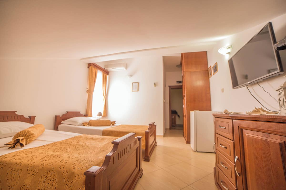 Ein Hotelzimmer mit zwei Betten, einem Fernseher, Holzmöbeln und einem Kühlschrank.