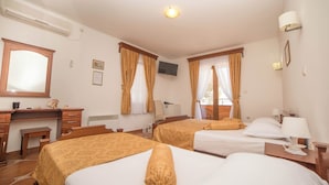 A hotel room with two beds, a desk, a chair, a TV, and a window with curtains. - Hotel Fiammanti (Đenovići)