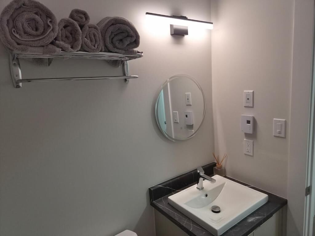 A bathroom with a sink, mirror, towel rack, and light fixture.