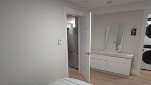 Un dormitorio con cama, armario, espejo y puerta que da a una cocina.