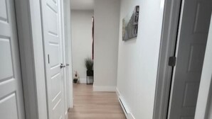 Un pasillo con puertas blancas, piso de madera y una planta en maceta.