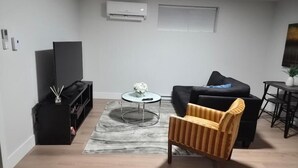 Una sala de estar con un sofá, una silla a rayas, una mesa de centro y un mueble negro para entretenimiento.