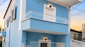 Un edificio de dos pisos con fachada azul, balcones blancos y techo de tejas rojas.