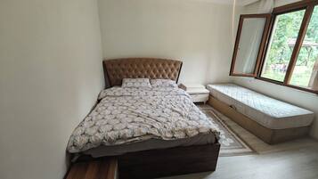 A bedroom with a bed, bedside tables, a bench, and a window with a view.