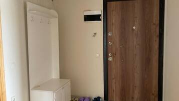 Una habitación con una puerta de madera, un armario blanco y un estante pequeño.