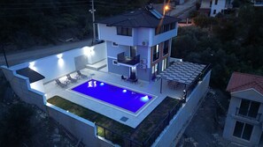 A modern two-story house with a rooftop pool, outdoor seating, and a well-lit patio area. - Villa Berk SARIGERME (Sarıgerme)
