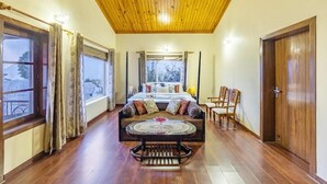 Um quarto com uma cama, um sofá, uma mesa redonda e teto de madeira.