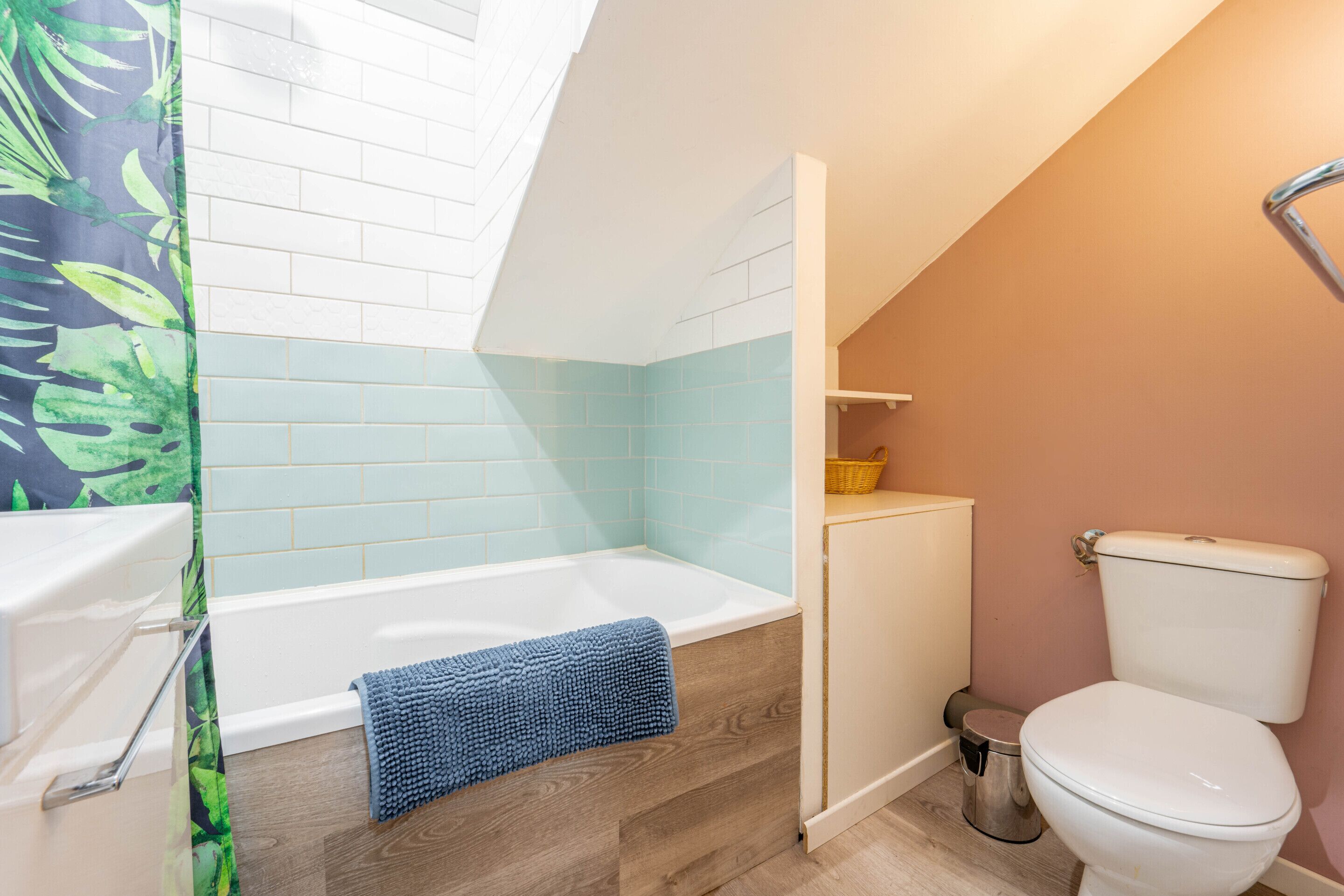 A bathroom with a bathtub, a toilet, and a shower curtain.