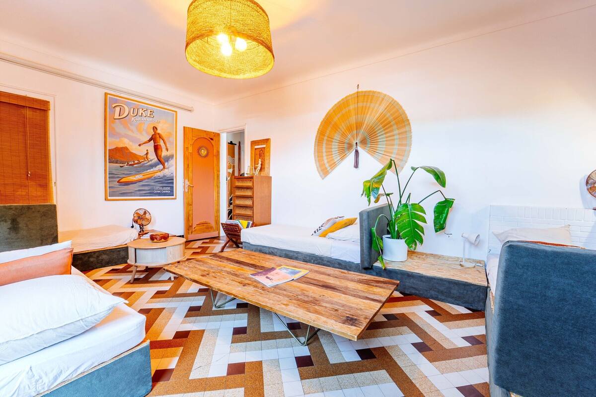 A modern hotel room with a bed, a wooden coffee table, a fan, and a poster on the wall.