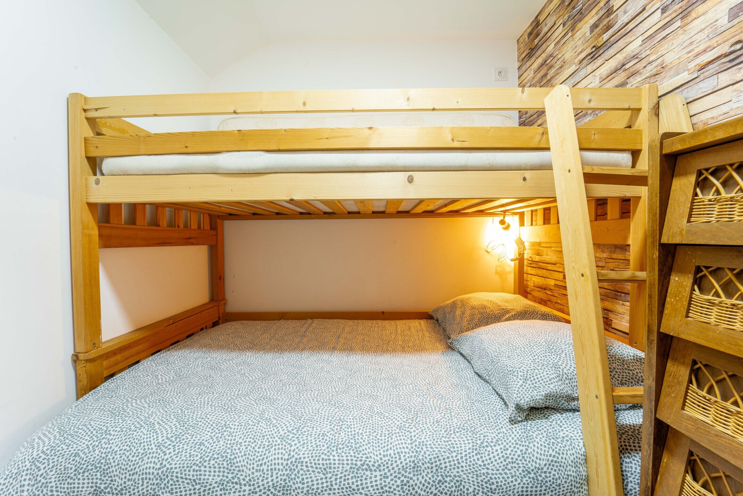A bunk bed with a wooden frame and a mattress with a patterned cover.